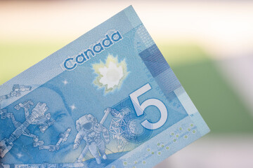 Close up of blue Canadian five (5) dollar bill with blurred defocused background. Macrophotography.