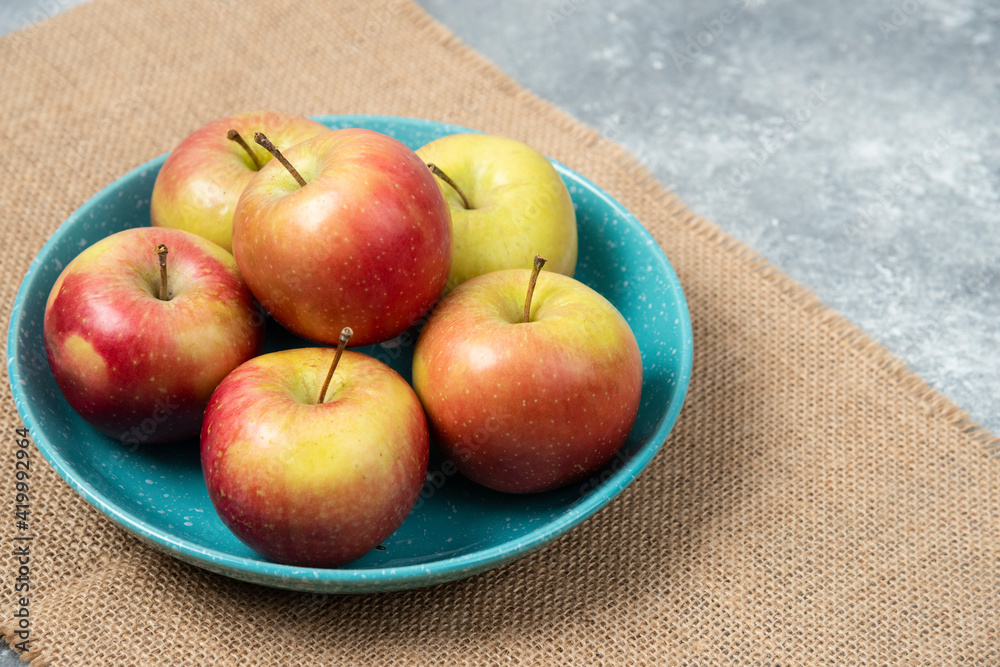 Wall mural blue bowl full of fresh apples on marble background