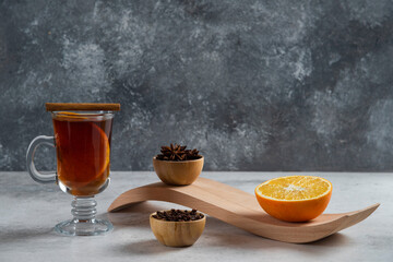 A glass cup of tea with slice of orange and dried loose teas