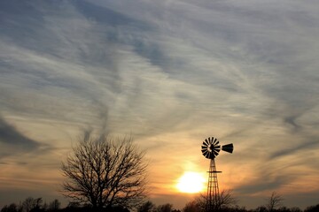 Kansas country Windmill silhouette with a colorful sky  and clouds north of Hutchinson Kansas USA out in the country.