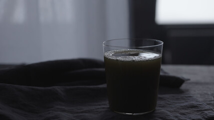 pour green matcha into tumbler glass on linen cloth