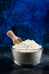 Glass bowl of flour on blue background