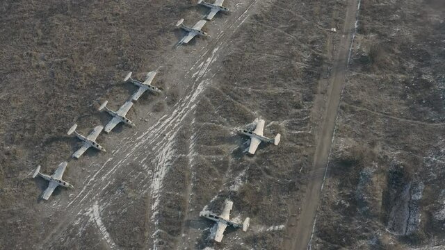 The formation of the wrecked aircraft - fighters and bombers from the Second World War - abandoned military airfield - aerial cinematic shot.