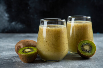 Two glass cups of tasty kiwi juice on a marble background