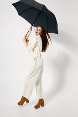 cheerful woman holding an umbrella in her hands white jumpsuit fashion studio boots © SHOTPRIME STUDIO