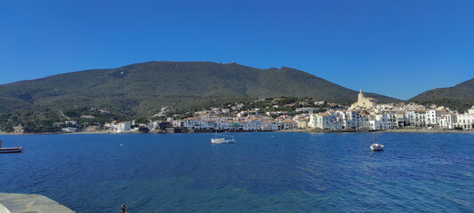 Vista parcial de Cadaques, entre el azul del cielo y el mar, con las montañas al fondo 