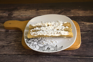 Tacos dorados called flautas with cream and cheese. Traditional Mexican food