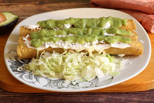 Tacos dorados called flautas with guacamole, lettuce, cream, cheese and avocado. Traditional Mexican food