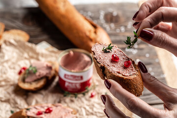 Close up Woman hands preparing and eating gourmet Belgian duck liver pate bread. Fresh homemade chicken liver pate on toasted bread with greens and pomegranate. place for text