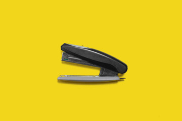 black metal and plastic stapler isolated on yellow back