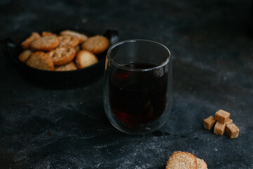 cookies in a metal plate with tea on a dark background