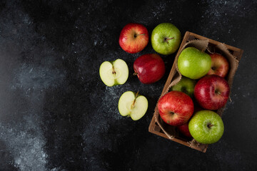 Wooden box of fresh organic apples on black background