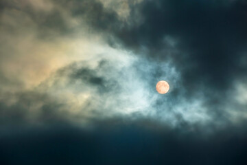 Obraz premium A large moon in a cloudy sky with thick clouds. Full moon. The night sky with the bright light of the full moon.Clouds at night time
