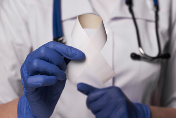 White ribbon in doctor hands for lung cancer day
