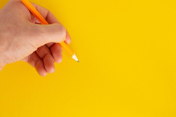 Hand holds a pencil on a colored background