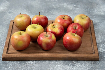Wooden board of fresh delicious apples on marble surface