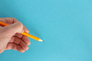 Hand holds a pencil on a colored background