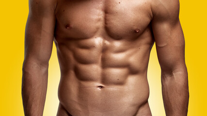 Closeup image of a strong athletic man showing muscular body and sixpack abs over yellow background. - obrazy, fototapety, plakaty
