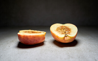 Slice of apple on black background.  The middle of the apple is rot. 