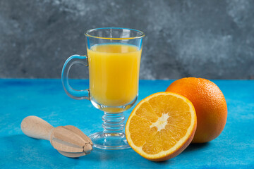 A glass cups of orange juice on a blue background