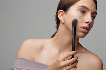 Fototapeta premium Portrait of young beautiful positive woman with nude make up and brush.