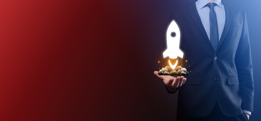 Startup business concept, Businessman holding tablet and icon rocket is launching and soar flying out from screen with network connection on dark background.