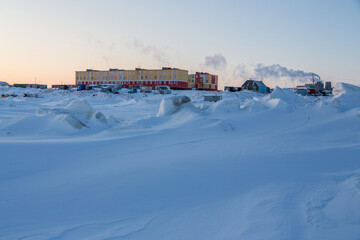 Winter arctic landscape.  View of a small arctic village on the shores of the frozen sea. Multi-colored residential buildings. Cold weather. Harsh polar climate. Tavayvaam, Chukotka, Siberia, Russia.