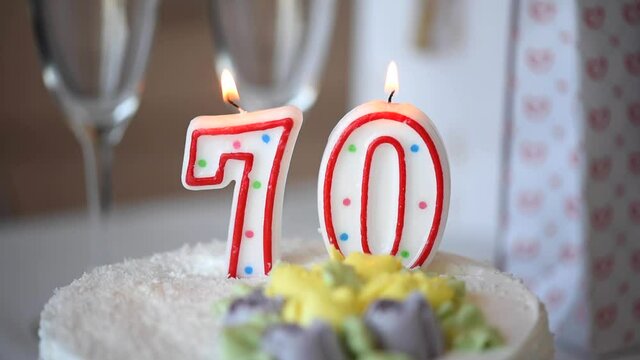 Birthday candle as number seventy 70 on top of sweet cake on the table, 70th birthday