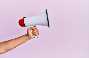 Hand of hispanic man holding megaphone over isolated pink background.