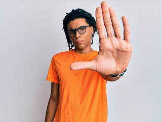 Young african american man wearing casual clothes and glasses doing stop sing with palm of the...