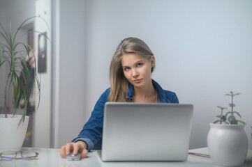 A girl with a laptop is studying at an online school. White room background