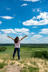 Fototapeta premium Happy, beautiful middle-aged woman with long hair on the background of a summer field. Healthy lifestyle and travel concept. Loneliness, unity with nature. toned