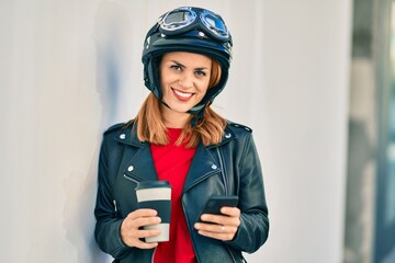 Young latin woman wearing motorcycle helmet using smartphone at the city.