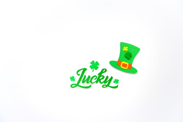 Lucky word - St. Patrick's day lettering. Brush calligraphy design with clover shamrock leaf and Leprechaun’s hat. Greeting cards. Soft focus. Top view.