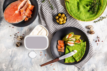 Green pancakes or crepes from spinach Served with salted salmon and soft cheese. Trendy vegetarian food