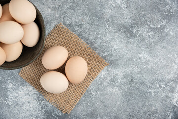 Wooden bowl of fresh organic raw eggs on marble surface