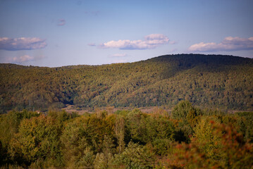 Naklejka na ściany i meble fall landscape overlooking the horizon where the ridges of the high mountains can be seen. high hills full of dense forests at sunset