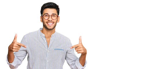 Young handsome man wearing casual clothes and glasses looking confident with smile on face,...