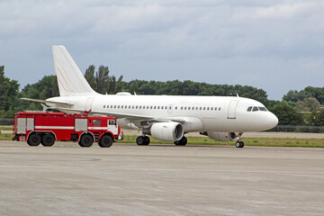 Passenger white plane and a fire truck at the airport. Place for text. Runway. Travel. Taxiing....