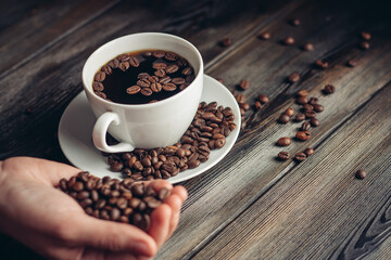 saucer with coffee beans and white cup on a wooden table side view Copy Space