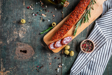 Fuets Catalan dry sausages. Set of spanish sausages and dry cured meat chistorra, chorizo, salchichon, fuet, olives, rosemary, chili peppers on a wooden background. top view