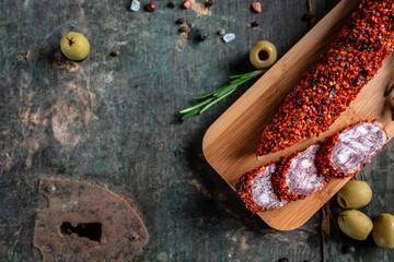 Fuets Catalan dry sausages. Set of spanish sausages and dry cured meat chistorra, chorizo, salchichon, fuet, olives, rosemary, chili peppers on a wooden background. top view - obrazy, fototapety, plakaty