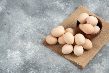 Wooden bowl of organic raw eggs on marble surface