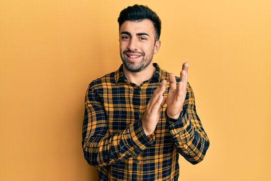 Young hispanic man wearing casual clothes clapping and applauding happy and joyful, smiling proud hands together