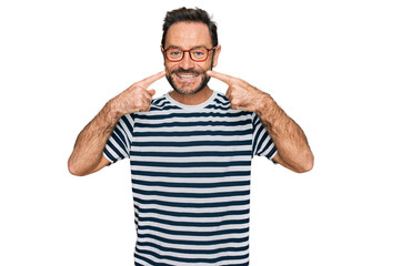 Middle age man wearing casual clothes and glasses smiling cheerful showing and pointing with fingers teeth and mouth. dental health concept.