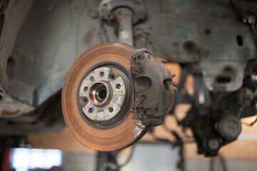Old and rusty car's suspension parts. Rusted disc brake and caliper on the car. Automotive industry and garage concepts. Selective focus