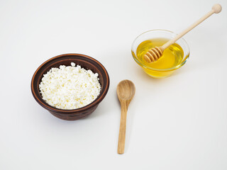 Fresh farm cottage cheese in a clay bowl with a wooden spoon and natural honey in a glass bowl with a honey ladle on a white background isolated. Delicious healthy breakfast. Diet food, weight loss