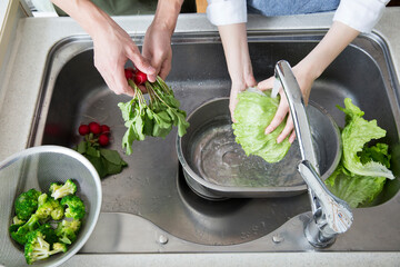 夫婦で料理　シンクで野菜を洗う
