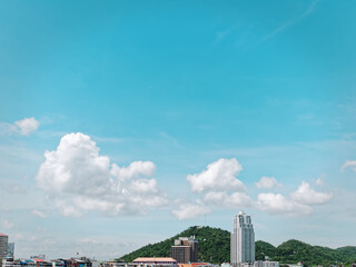 Tranquil Scenery of Cityscape with Green Mountain Hill and Cloudy Blue Sky