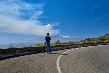 a person stops on the road that leads to Taormina to admire the Etna volcano in Sicily